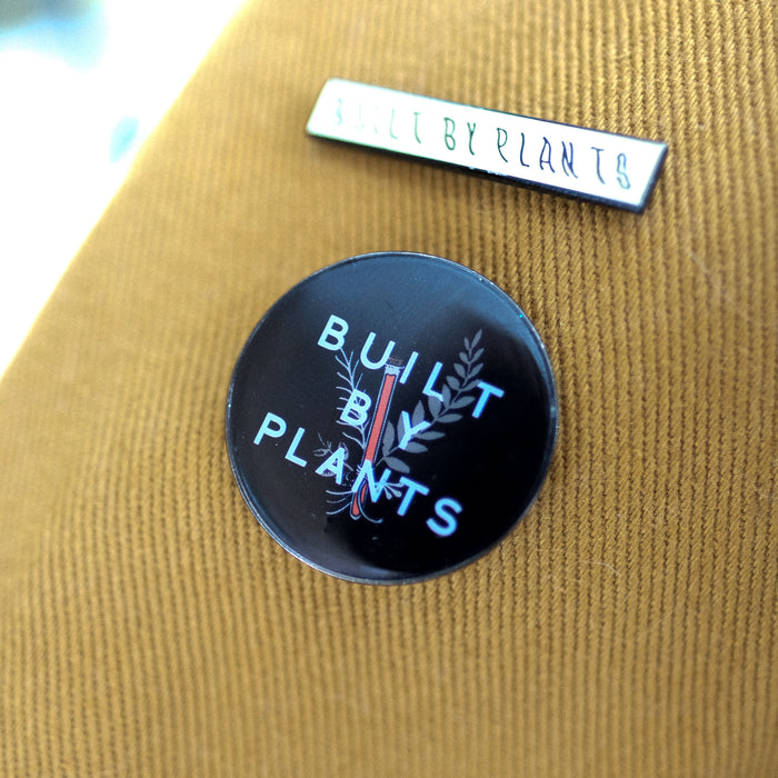 Built by Plants black circle enamel pin on brown clothing