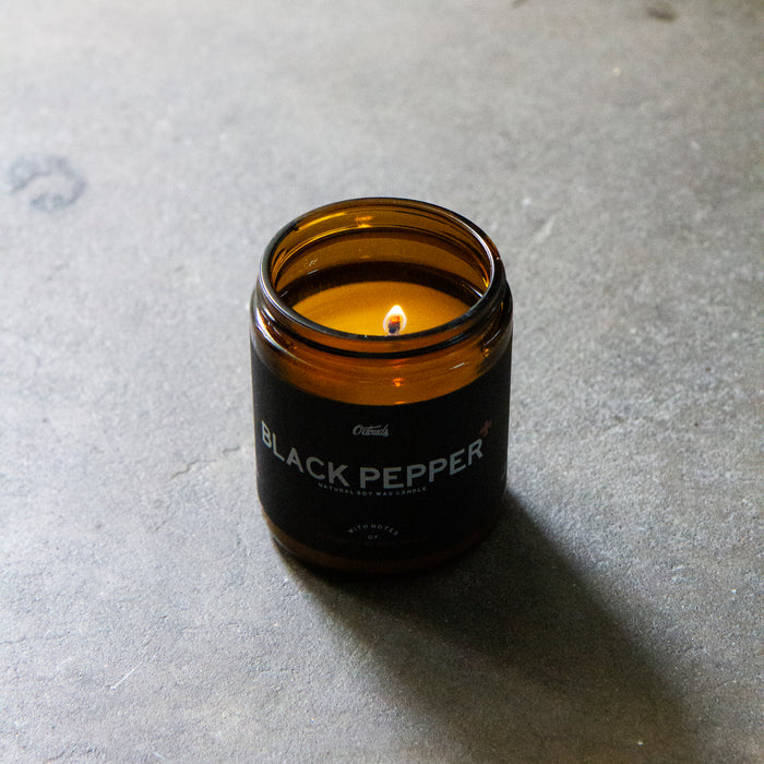 Black Pepper lit candle  amber glass container overhead shot on grey background