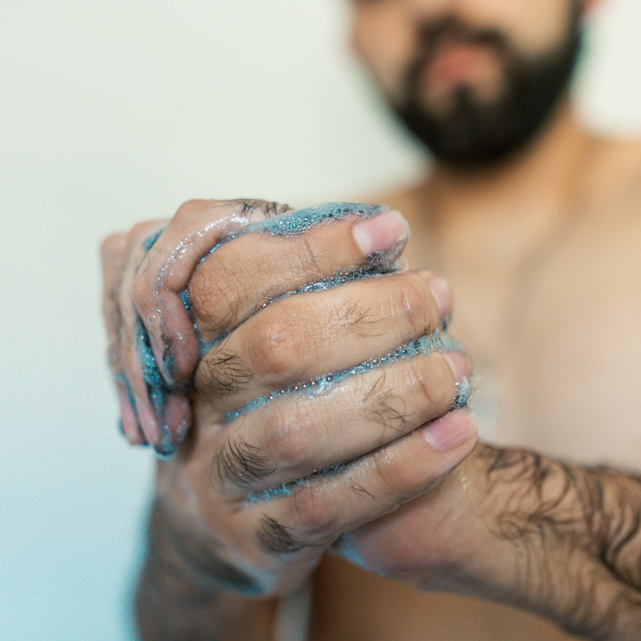 Hands in focus lathering grey-black charcoal shampoo together